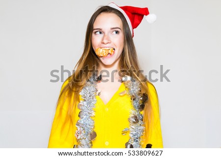 Amazing funky teen woman posing against white wall background in santa claus hat and decorates, make grimaces. Bright make up, full lips. Surprised emotions. Isolated background.