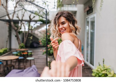 Amazing Girl With Stylish Haircut Looking Over Shoulder. Outdoor Photo Of Cute Tanned Female Model Wears Elegant Pink Dress.