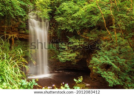 Amazing Glencar Waterfall surrounded by green foliage. County Lietrim, Ireland. Popular tourist attraction