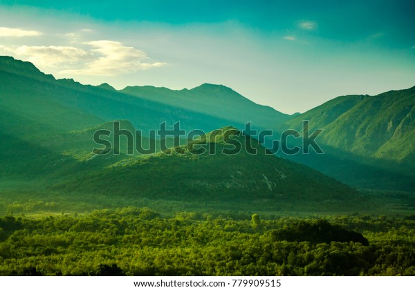 Amazing green foggy valley covered with forest and mountains in the background
