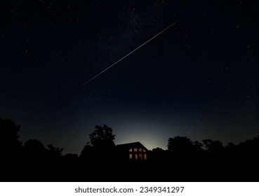 Amazing green and pink meteor trail streaking across night sky over a house in rural area  - Powered by Shutterstock