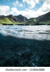 Amazing Half Underwater Half Above Photo Showing Beautiful Scenic Mountains On Bright Sunny Day And Clear Blue Ocean Water With Rocks And Reef 