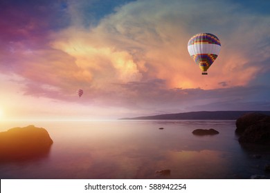 Amazing heavenly background - two colorful hot air balloons flies in glowing sunset sky above calm sea