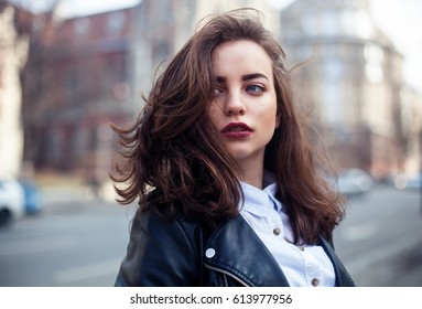 Amazing joyful pretty girl with long brunette hair. posing outdoor. leather jacket,brunette hair, bright red lips Close up fashion street stile portrait Model looking aside