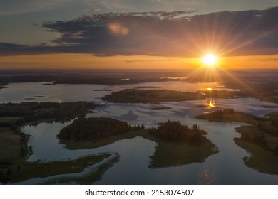 Amazing lake land from above, beautiful islands covered with trees and meadows in morning sunlight. Aerial, flight over Braslav Lakes National Park during fantastic sunrise. Colorful clouds on horizon