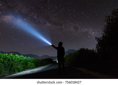An Amazing Milky Way And Stargazing With A Silhouette Man Flashing The Light Towards The Stars. 