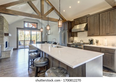 Amazing modern and rustic luxury kitchen with vaulted ceiling and wooden beams, long island with white quarts countertop and dark wood cabinets.