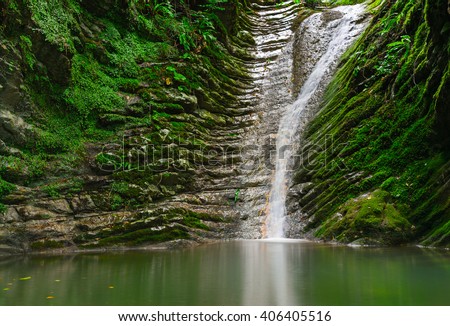 Amazing natural view of small waterfall in tropical green forest landscape. Scenery of russian nature, river and lake in forest with awesome water. Concept of tourism in Russia and nature ecology.