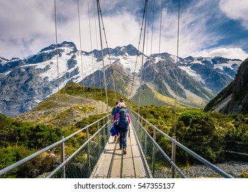 Amazing Nature Of Hooker Valley Track In Mount Cook, New Zealand. Young Family Walk On Suspension Bridge.