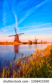 Amazing nature, scenic sunset landscape, windmills, blue sky and water. Traditional dutch countryside, famous village of mills Kinderdijk, popular tourist attraction in Netherlands. Vertical image