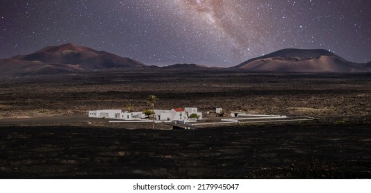 Amazing nocturnal panoramic landscape of volcano craters in Timanfaya national park. Milky way stars on night sky over La Gueria, Lanzarote island, Canary islans, Spain