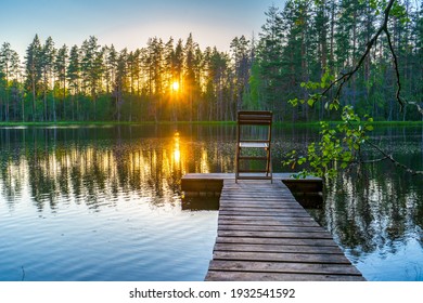 Amazing Northern Landscape Of Lake And Forest In Summer Evening At Sunset With Chair On Wooden Planked Footway At Pond. Wonderful Nature. Leisure, Vacation, Weekend Getaway, Staycation Concept.