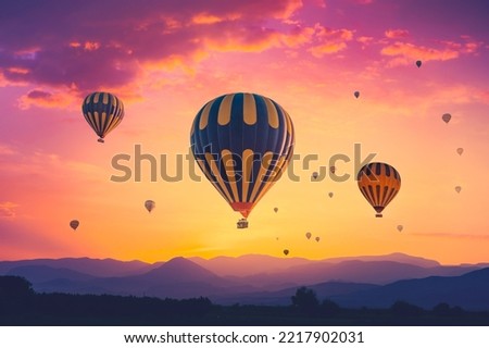 Amazing pink orange sunrise with colorful hot air balloons over spectacular mountain range in morning fog. Background for your travel concept. Natural summer scenery, morning sun rise watching