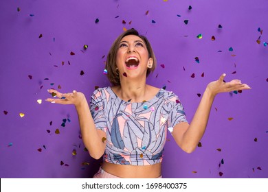 Amazing portrait of a young girl in the studio under a shower of confetti - Isolated on a colorful dark purple background - Shutterstock ID 1698400375
