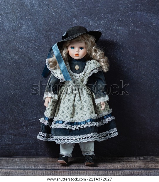 Amazing realistic vintage toy with blue\
eyes.The doll dressed in a white-blue dress with lace and has a\
blond hair. Selective focus. Porcelain\
doll.