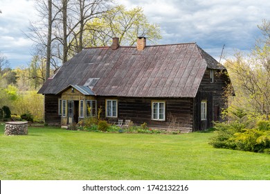 Amazing restored old traditional farm house in Mikko farm South Estonia. Beautiful garden around historic timber construction homestead building. Dark color log cabin as a old farm shed.