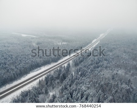 Amazing road in the frozen winter forest with driving cars. Foggy vanishing point perspective. Aerial panoramic view on the north. 