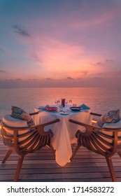 Amazing Romantic Dinner On The Beach On Wooden Deck With Candles Under Sunset Sky. Romance And Love, Luxury Destination Dinning, Exotic Table Setup With Sea View