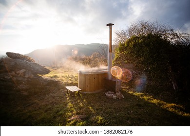 Amazing romantic location for steaming hot tub warmed by fire wood. Glamping staycaion vacation destination. Steam come out of outdoors hot tub at spa resort in woods nature