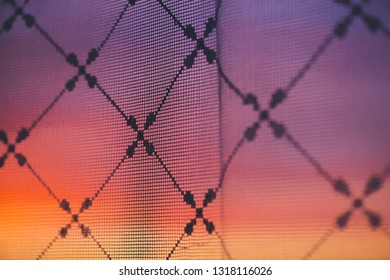 Amazing romantic sunset in window behind silhouettes of tulle texture. Wonderful pink orange violet dawn sky from window through patterned curtain. Cosiness background of scenic sunrise. Copy space. - Powered by Shutterstock