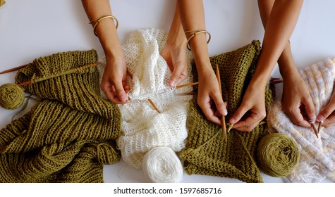 Amazing Scene From Indoor Top View, Group Of Woman Hand With Knitting Needles To Knit Wool White And Mossy Green Scarf On White Background For Winter Handmade Gift, Funny Scene For Winter Concept 