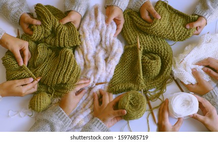 Amazing Scene From Indoor Top View, Group Of Woman Hand With Knitting Needles To Knit Wool White And Mossy Green Scarf On White Background For Winter Handmade Gift, Funny Scene For Winter Concept 