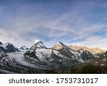 Amazing scenery in evening, beautiful mountains area with white snow. Gorgeous mountain ridge with high rocky peak Dent Blanche with shining stars in sky, wonderland.
