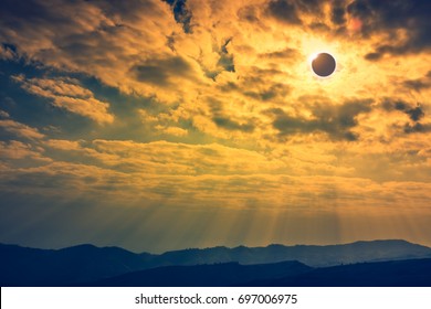 Amazing scientific natural phenomenon. The Moon covering the Sun. Total solar eclipse with diamond ring effect glowing on sky above mountain range. Serenity nature background.