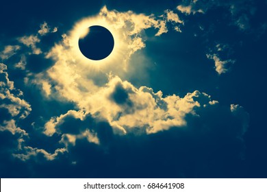 Amazing scientific natural phenomenon. Total solar eclipse with diamond ring effect glowing on sky with dark clouds. Abstract fantastic background of beautiful nature and serenity landscape.