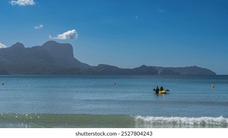 Amazing seascape. Day. The turquoise ocean is calm. The waves are foaming at the shore of the beach. A canoe with people on the water. Picturesque mountains against a clear blue sky. Copy space.  - Powered by Shutterstock