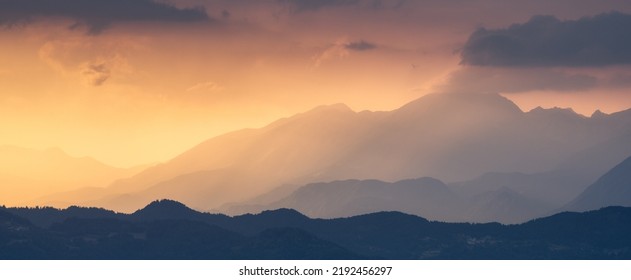 Amazing silhouettes of a mountains at colorful sunset in summer in Slovenia. Landscape with mountain ridges in fog, golden sunlight and clouds in the evening. Nature. Hills in sunlight. Scenery - Powered by Shutterstock