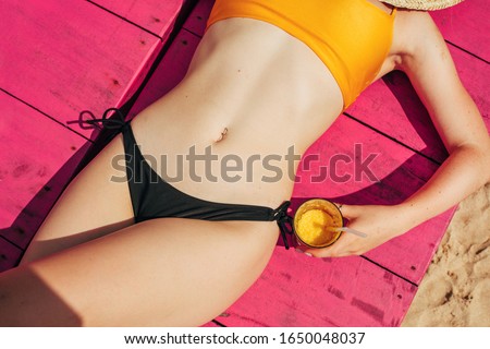 Amazing slim attractive body lying on pink towel and get sunbathe. Rest on beach during vacation period. Tropical islands or countries. Well-built feminine bidy. Sun shines on it. Cut view