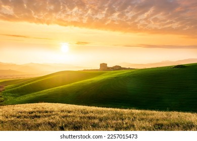 amazing sunset among green spring hills in highland farm with castle , mountains and picturesque colorful sunset on background of landscape