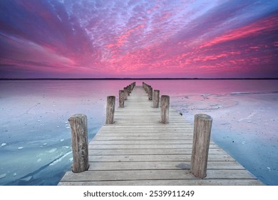 amazing sunset light over an old wooden pier with frozen sea, cold winter landscape with ice and snow                                - Powered by Shutterstock