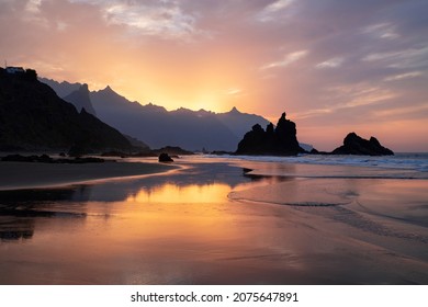 Amazing sunset with spectacular dramatic purple color sky reflecting into the water pools and the neat sand surface on the secluded Benijo beach or Playa de Benijo, in Tenerife, Canary Islands, Spain - Powered by Shutterstock