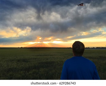 Amazing sunset while a man flies a remote control airplane.