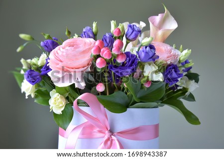 Amazing tender bouquet with pink ranunculus, violet Alstroemeria flowers and tiny white roses in cardboard box with pink ribbon. Beautiful bunch of spring flowers. Easter gift. Seasonal spring flowers