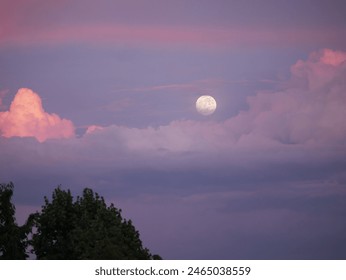 Amazing view of big full moon rising above pink and purple colored storm clouds. Wonderful colors of blue hour after summer sunset. Dreamy moment of mystic moonrise among colorful cumulus clouds. - Powered by Shutterstock