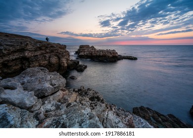 Amazing view with colorful sunrise sky and a silhouette of a photographer at the rocky coastline of the Black Sea - Powered by Shutterstock