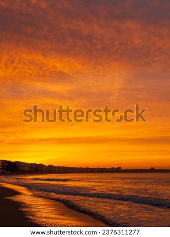 Amazing view of a fiery sunrise with multicolored clouds. Sea waves along the seashore at sunrise. Morning time. Ocean view. La Baule-Escoublac, France