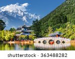 Amazing view of the Jade Dragon Snow Mountain and the Black Dragon Pool, Lijiang, Yunnan province, China. The Suocui Bridge over pond and the Moon Embracing Pavilion in the Jade Spring Park.
