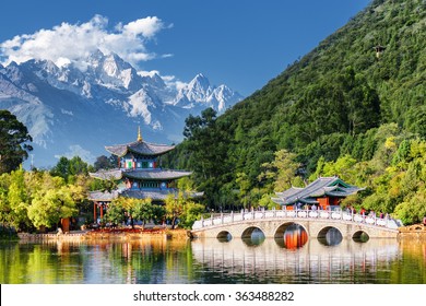 Amazing view of the Jade Dragon Snow Mountain and the Black Dragon Pool, Lijiang, Yunnan province, China. The Suocui Bridge over pond and the Moon Embracing Pavilion in the Jade Spring Park. - Powered by Shutterstock