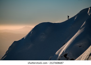 Amazing view of a snow-covered hill with powdery snow and a man skier on it. Picturesque landscape and the sky in the background. Ski touring and freeride concept