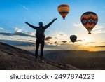 Amazing view with sport sitting girl and a lot of hot air balloons. National park Anatolia, Cappadocia, Turkey. Artistic picture. Beauty world. The feeling of complete freedom.