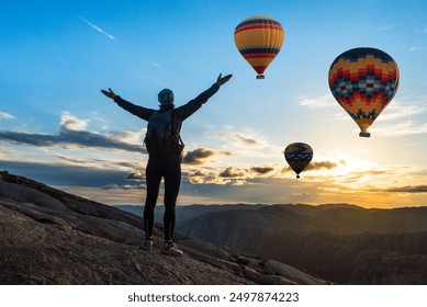 Amazing view with sport sitting girl and a lot of hot air balloons. National park Anatolia, Cappadocia, Turkey. Artistic picture. Beauty world. The feeling of complete freedom.