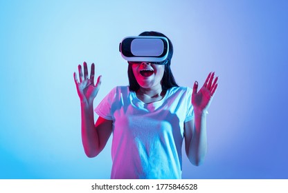 Amazing virtual world. Surprised girl with vr glasses and open mouth, raises hands up in neon light, copy space, copy space - Shutterstock ID 1775846528