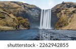 Amazing Skógafoss waterfall with long exposure and tourist at the base of the waterfall during winter, South coast Iceland