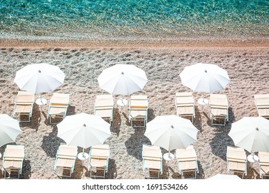 Amazing White Beach In The Natural Reserve From Above View. White Umbrellas And Beach Loungers