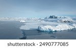 Amazing winter wild nature landscape in Antarctica. Snow covered icebergs and mountain range under blue sky. Frozen polar ocean surface background. Antarctic travel, exploration. Discover South Pole