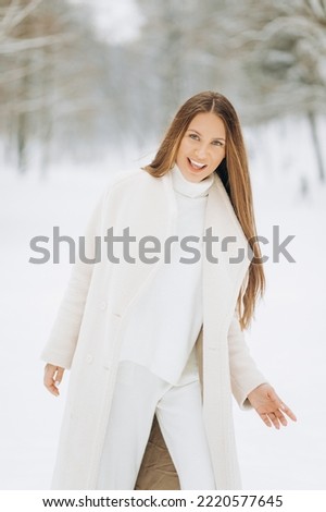 Amazing woman with long hair in a stylish beige coat. Photo of a cheerful young woman on a walk